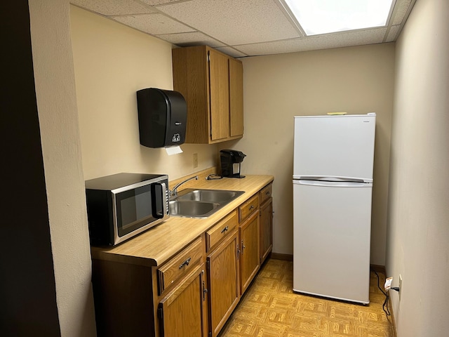 kitchen featuring a paneled ceiling, sink, white fridge, and light parquet floors