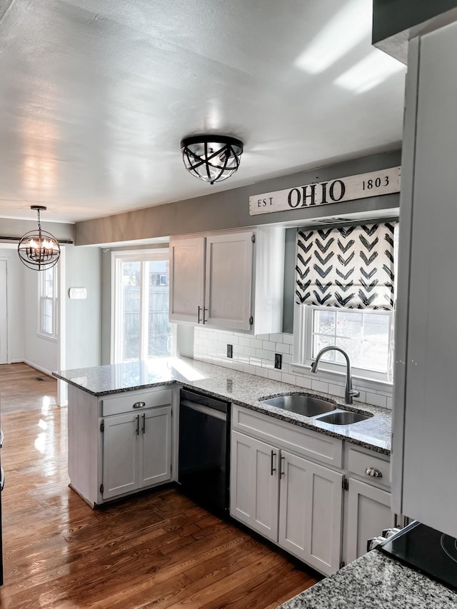 kitchen with white cabinetry, sink, dark hardwood / wood-style flooring, stainless steel dishwasher, and decorative light fixtures