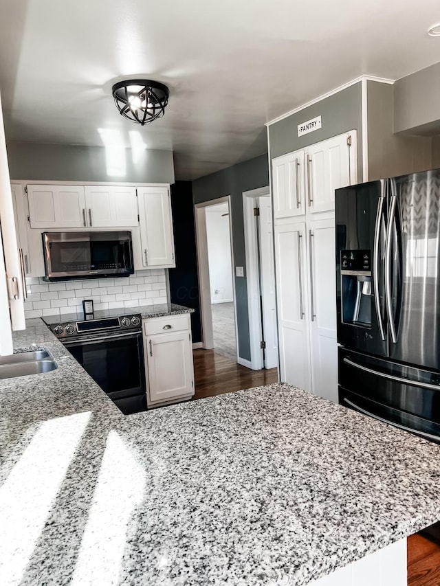 kitchen featuring light stone countertops, white cabinetry, and stainless steel appliances