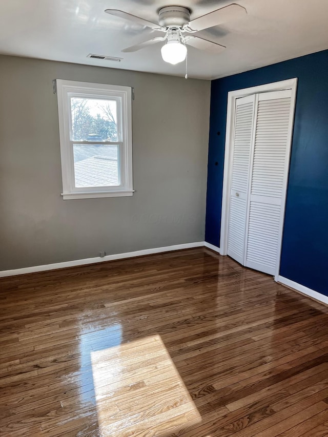 unfurnished bedroom with ceiling fan, dark wood-type flooring, and a closet