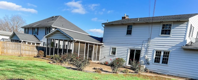 rear view of property featuring a yard and a sunroom