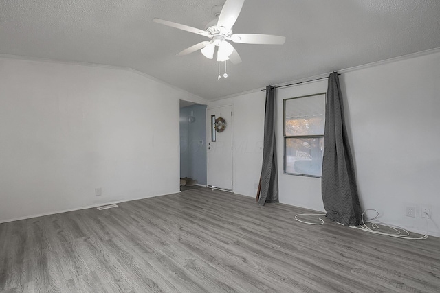 empty room with ceiling fan, light wood-type flooring, a textured ceiling, and vaulted ceiling