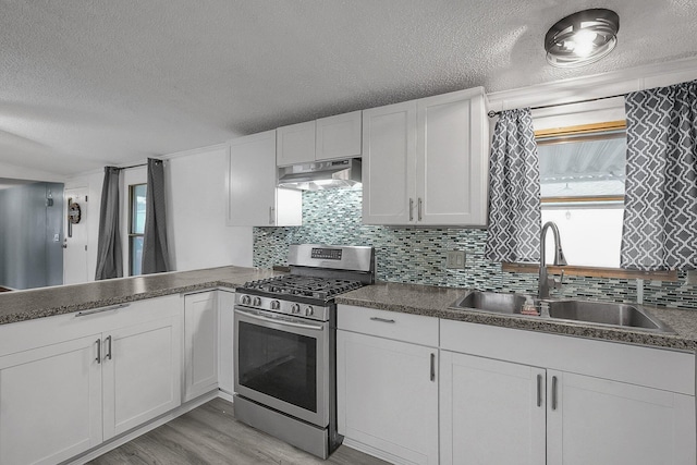 kitchen with gas stove, sink, backsplash, light hardwood / wood-style floors, and white cabinets