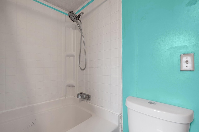 bathroom featuring a textured ceiling, toilet, and tiled shower / bath