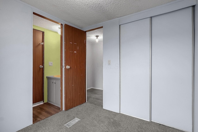 unfurnished bedroom with a textured ceiling, a closet, and dark wood-type flooring