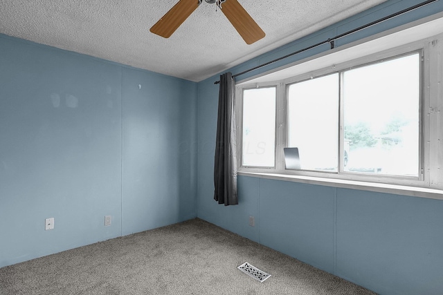 carpeted empty room featuring a textured ceiling and ceiling fan