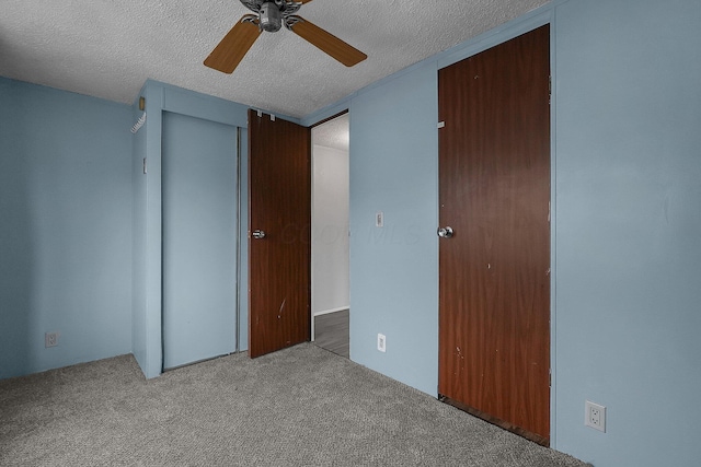 unfurnished bedroom with a closet, a textured ceiling, light colored carpet, and ceiling fan