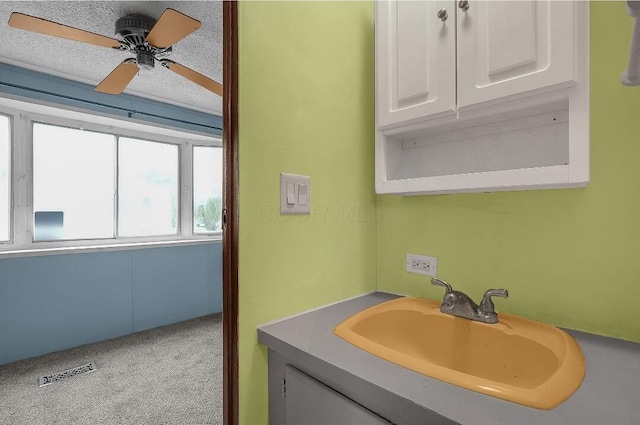 bathroom with ceiling fan, vanity, and a textured ceiling