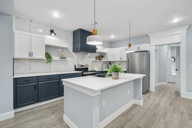 kitchen featuring white cabinets, an island with sink, decorative light fixtures, light hardwood / wood-style floors, and stainless steel appliances