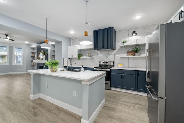 kitchen with decorative light fixtures, ceiling fan, appliances with stainless steel finishes, and light hardwood / wood-style flooring