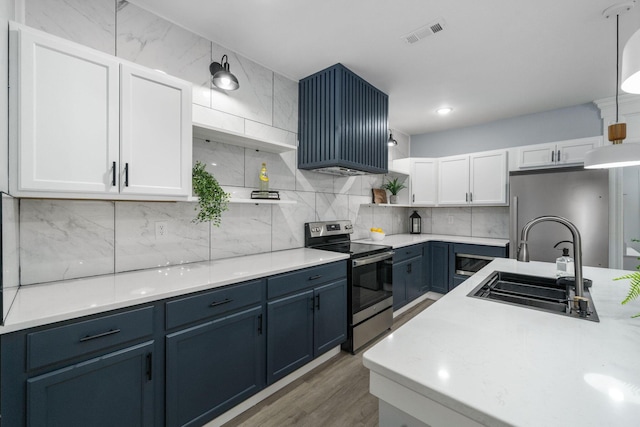 kitchen featuring stainless steel appliances, sink, decorative light fixtures, white cabinets, and hardwood / wood-style floors