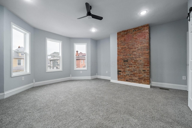 unfurnished room featuring carpet flooring, ceiling fan, and a barn door