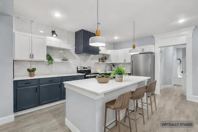 kitchen with a kitchen island with sink, tasteful backsplash, a kitchen bar, white cabinetry, and stainless steel appliances