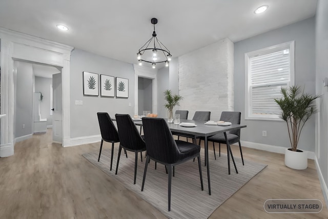 dining area with light hardwood / wood-style flooring and an inviting chandelier