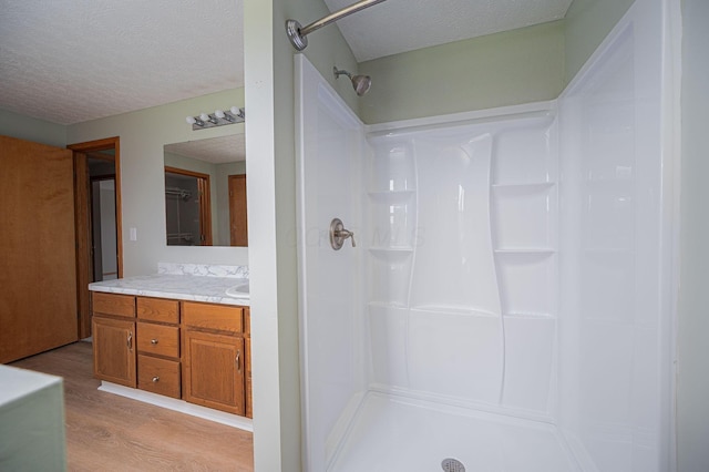 bathroom with a shower, hardwood / wood-style floors, vanity, and a textured ceiling