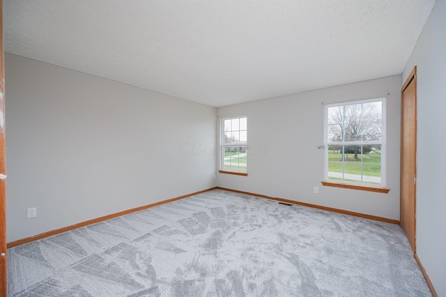 unfurnished room featuring plenty of natural light, carpet floors, and a textured ceiling