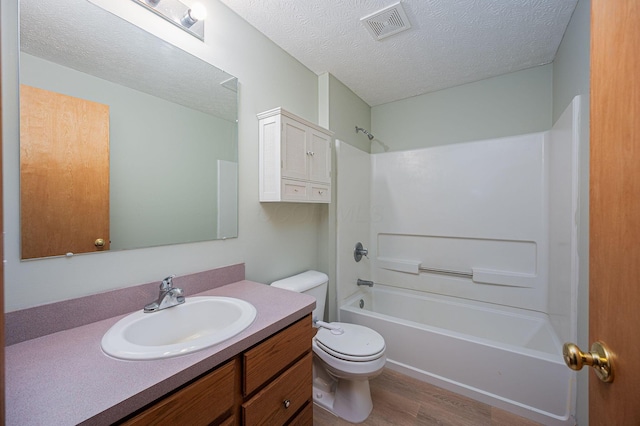 full bathroom with hardwood / wood-style floors, vanity, bathtub / shower combination, toilet, and a textured ceiling