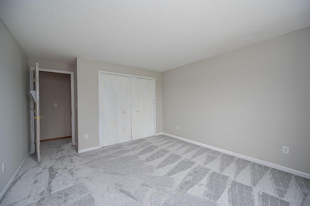 unfurnished bedroom with a textured ceiling, light colored carpet, and a closet