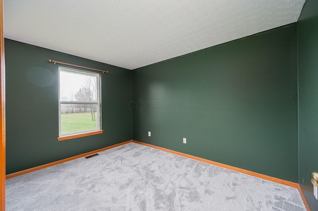 carpeted empty room with a textured ceiling