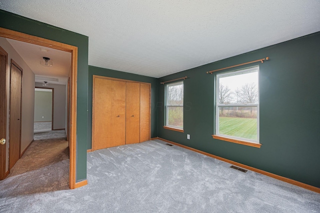 unfurnished bedroom featuring light colored carpet, a textured ceiling, and a closet