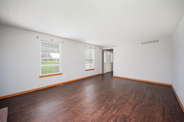 spare room featuring a textured ceiling and dark hardwood / wood-style flooring