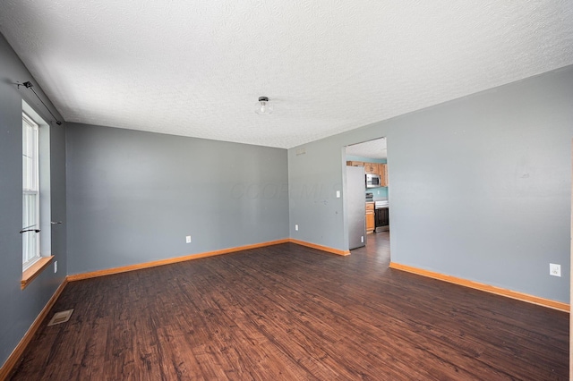 empty room with a textured ceiling and dark wood-type flooring