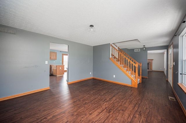 spare room featuring a textured ceiling, a fireplace, and dark hardwood / wood-style floors