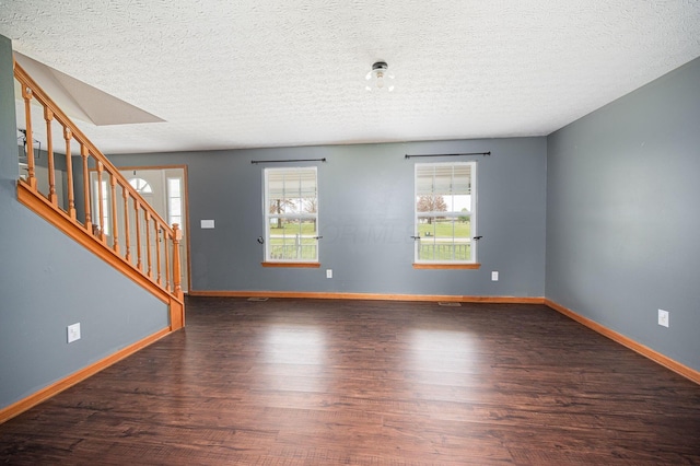 unfurnished room featuring dark hardwood / wood-style floors, a healthy amount of sunlight, and a textured ceiling