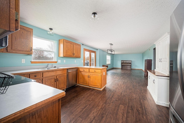 kitchen with a wealth of natural light, dark hardwood / wood-style floors, kitchen peninsula, and appliances with stainless steel finishes