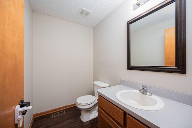 bathroom with hardwood / wood-style flooring, vanity, toilet, and a textured ceiling