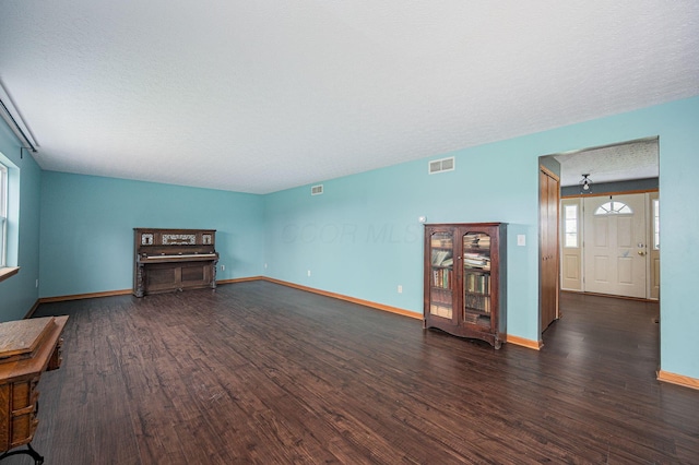 unfurnished living room with dark hardwood / wood-style flooring and a textured ceiling