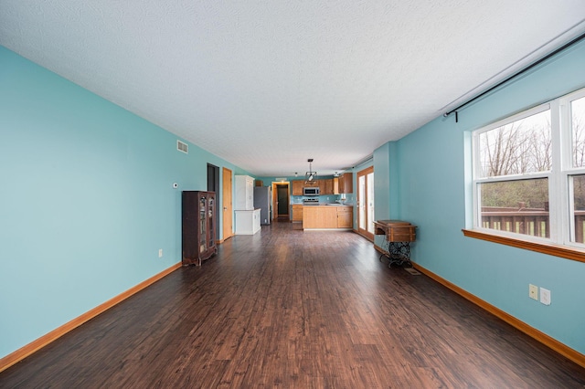 unfurnished living room featuring a textured ceiling and dark hardwood / wood-style flooring