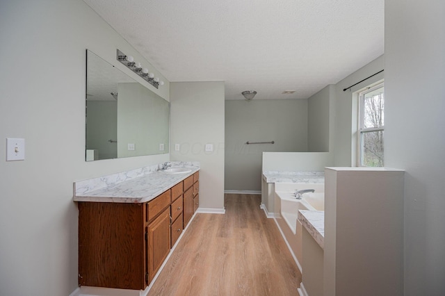 bathroom with a tub, hardwood / wood-style floors, vanity, and a textured ceiling