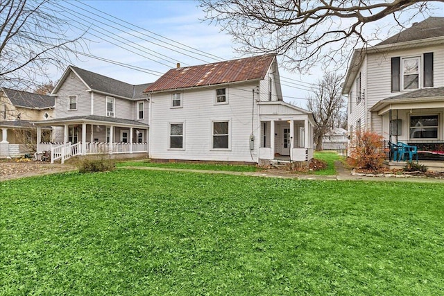 back of house featuring a lawn and covered porch