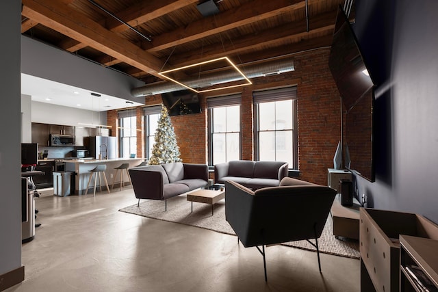 living room featuring beam ceiling and brick wall