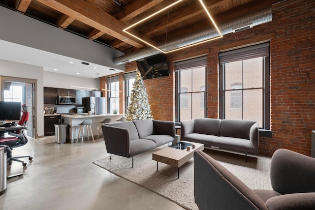 living room featuring a healthy amount of sunlight, sink, and brick wall