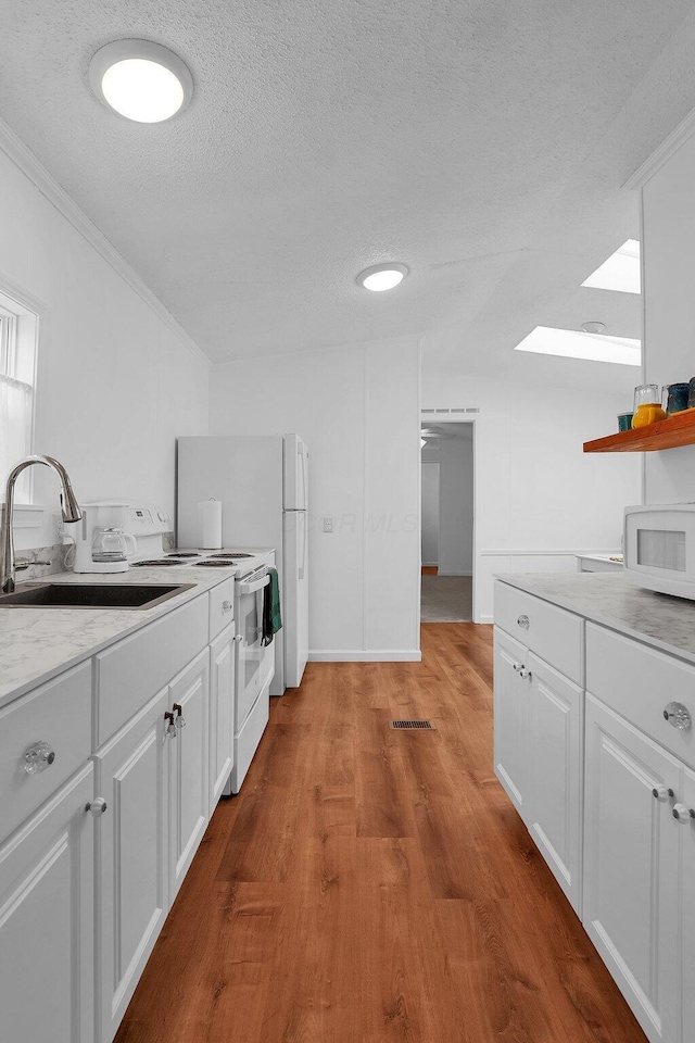 119 Skyline Dr, South Bloomfield, OH 43103 - kitchen with a textured ceiling, white appliances, light countertops, white cabinetry, and wood finished floors