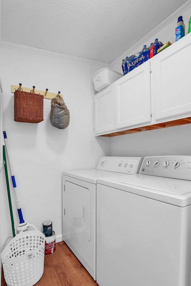 clothes washing area with separate washer and dryer, light hardwood / wood-style flooring, cabinets, and a textured ceiling