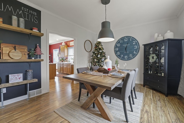 dining space featuring crown molding, hardwood / wood-style flooring, and sink