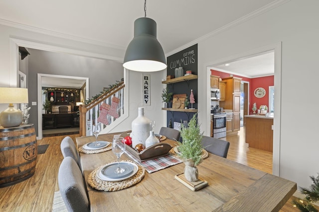 dining area with ornamental molding and light hardwood / wood-style flooring