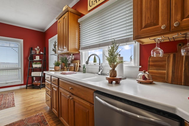 kitchen featuring ornamental molding, light hardwood / wood-style floors, stainless steel dishwasher, and sink