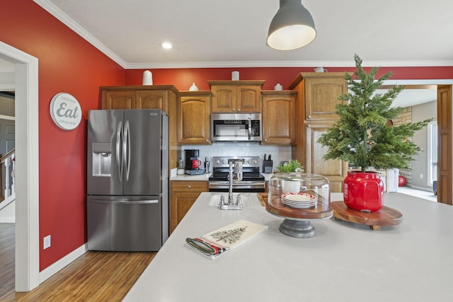 kitchen featuring hardwood / wood-style floors, appliances with stainless steel finishes, ornamental molding, and tasteful backsplash