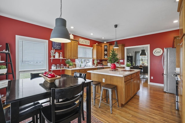 kitchen featuring a kitchen island, light hardwood / wood-style floors, stainless steel appliances, and decorative light fixtures