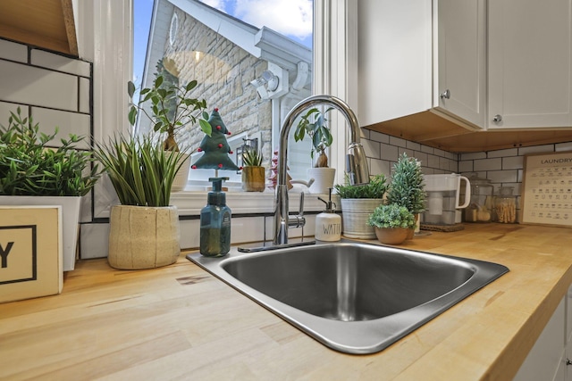 interior details with decorative backsplash, sink, and white cabinets