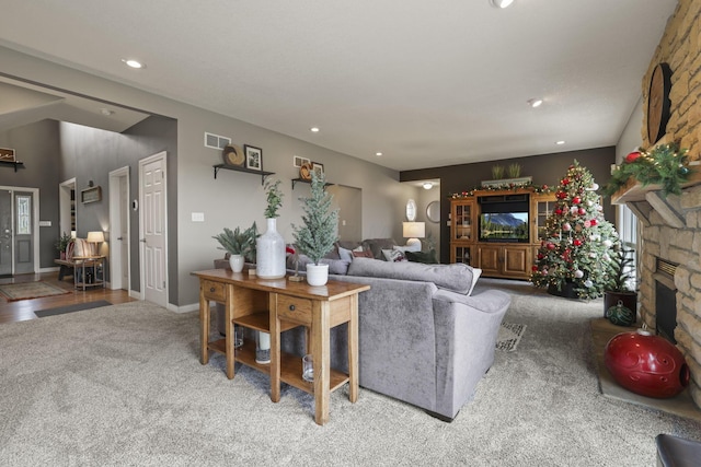 carpeted living room with a stone fireplace