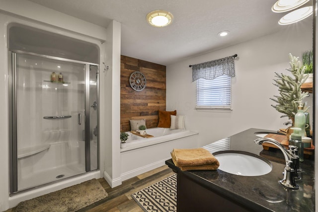 bathroom featuring hardwood / wood-style flooring, wooden walls, plus walk in shower, a textured ceiling, and vanity