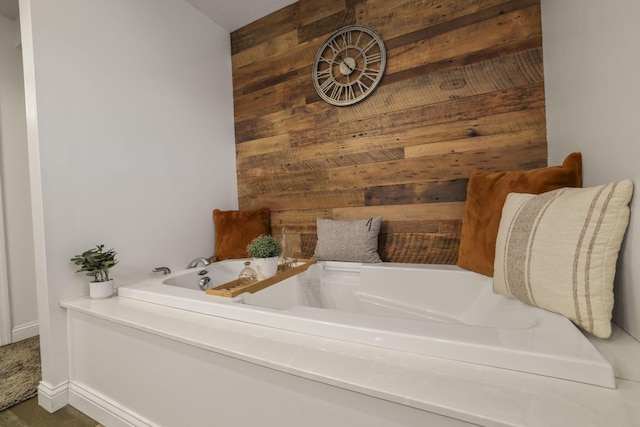 bathroom with a bath and wood walls