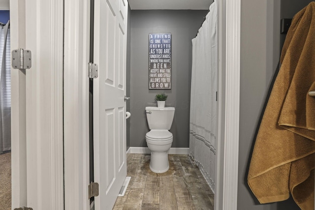 bathroom with toilet, a shower with shower curtain, and hardwood / wood-style flooring