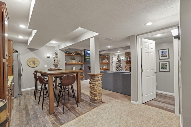 dining area featuring a textured ceiling, hardwood / wood-style floors, and a stone fireplace