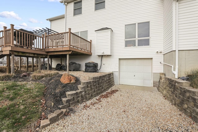 rear view of house featuring a pergola, a wooden deck, and a garage